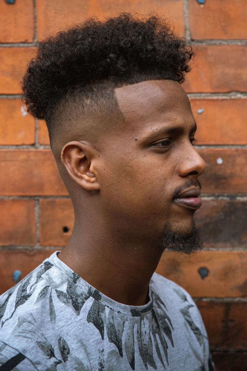 High skin fade with curly top and a sharp line-up
